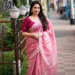 A woman in a light pink Pure Tussar silk saree with a wide silver embroidered floral border and small white buttis, paired with a magenta embroidered blouse.