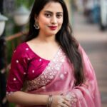 A woman in a light pink Pure Tussar silk saree with a wide silver embroidered floral border and small white buttis, paired with a magenta embroidered blouse.