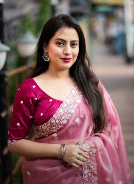 A woman in a light pink Pure Tussar silk saree with a wide silver embroidered floral border and small white buttis, paired with a magenta embroidered blouse.