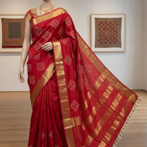 A mannequin wearing a red Kota silk Bhagalpuri saree featuring white geometric square embroidery, a thick gold zari border, and cream tassels.