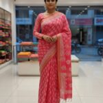 An Indian model showcases a vibrant pink Kota Silk Bhagalpuri saree from Bhavya Lakshmi Fabrics featuring a white traditional Bagru block print, a structured zari border, and a matching long-sleeved blouse.
