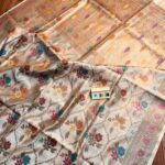 Natural beige pure Bhagalpuri Munga silk saree from Bhavya Lakshmi Fabrics featuring a multi-color floral Meenakari jaal and an intricate gold zari border