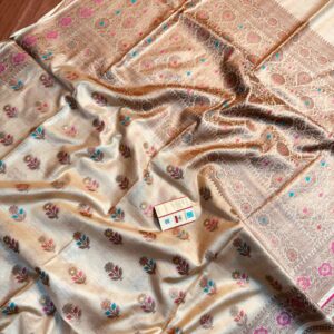 Natural beige gold pure Bhagalpuri Munga silk saree from Bhavya Lakshmi Fabrics featuring multi-color floral Meenakari butis and an intricate gold zari border, spread on a wooden floor