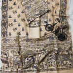 An unstitched cream Katan silk suit material set by Bhavya Lakshmi Fabrics featuring detailed multi-colored Madhubani prints of ceremonial figures, elephants, and peacocks in indigo blue and olive green.