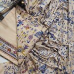 An unstitched beige Katan silk suit material set by Bhavya Lakshmi Fabrics featuring extensive royal blue, pink, and yellow Warli tribal festive prints with patterned borders.