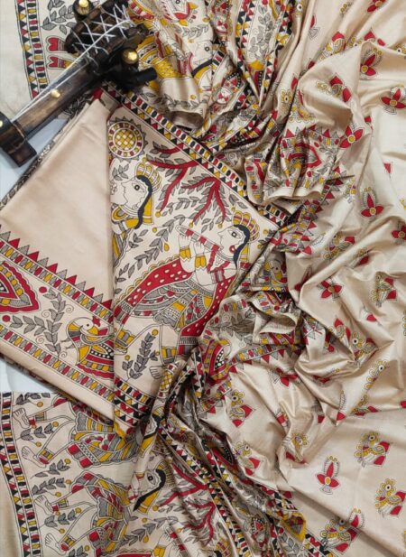 A premium unstitched beige Katan silk suit material set by Bhavya Lakshmi Fabrics featuring detailed multicolored Madhubani art prints of fluting deities, birds, and fish on a clean, minimal off-white backdrop.