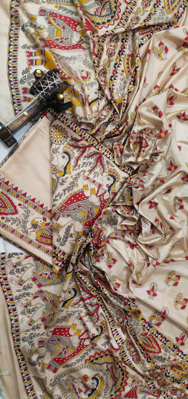 Beige and Terracotta Madhubani Print Unstitched Katan Silk Suit Material A premium unstitched beige Katan silk suit material set by Bhavya Lakshmi Fabrics featuring detailed multicolored Madhubani art prints of fluting deities, birds, and fish on a clean, minimal off-white backdrop.
