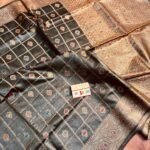Sophisticated midnight black pure Bhagalpuri Munga silk saree from Bhavya Lakshmi Fabrics featuring gold zari checks with multi-color floral Meenakari butis and an intricate gold zari border