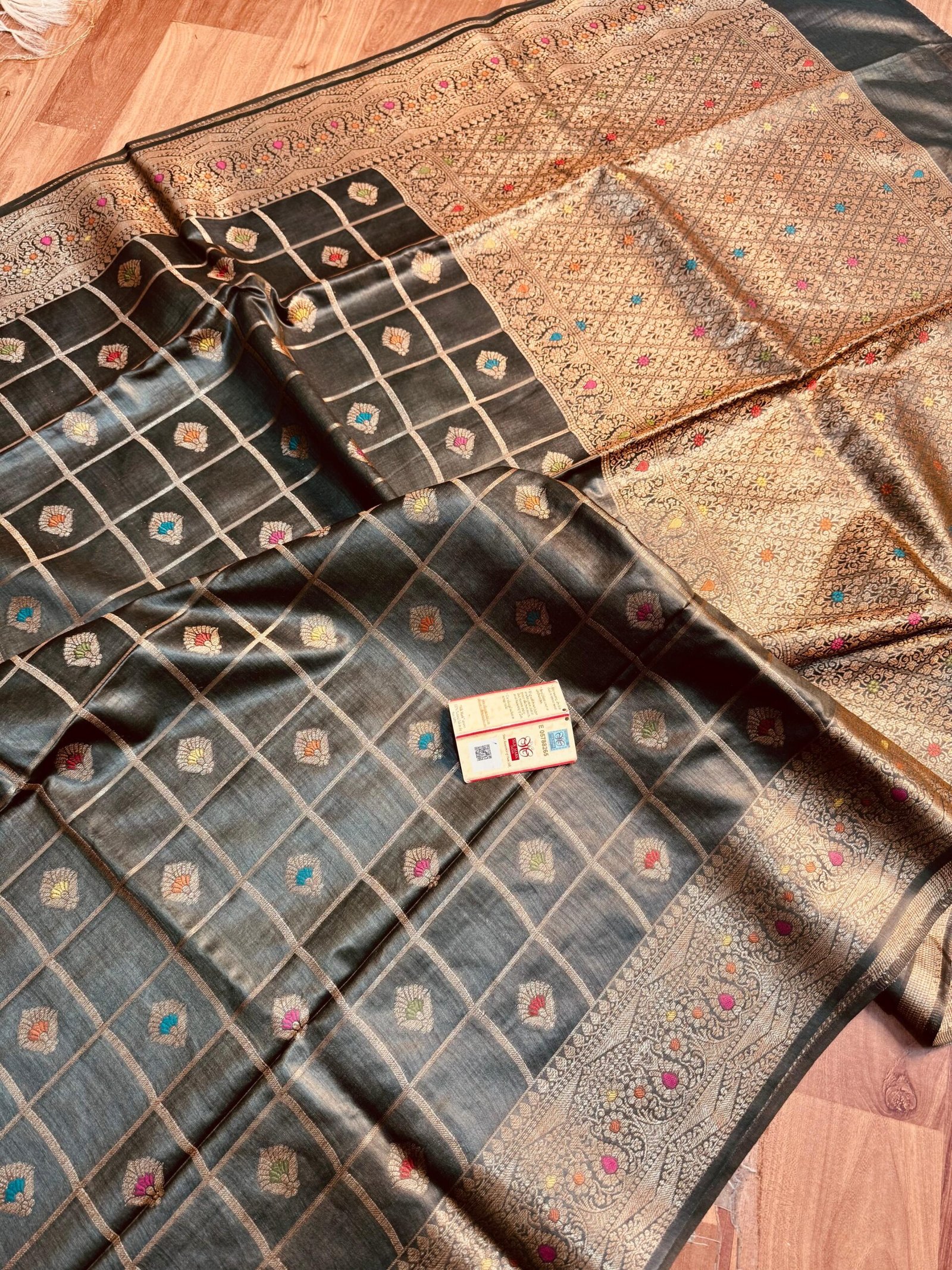 Bhavya Lakshmi Fabrics Midnight Black Pure Munga Silk Saree Hand-Woven Meenakari Checks Sophisticated midnight black pure Bhagalpuri Munga silk saree from Bhavya Lakshmi Fabrics featuring gold zari checks with multi-color floral Meenakari butis and an intricate gold zari border