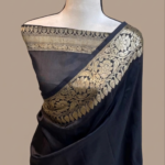 Midnight black Banarasi Katan silk saree with a plain solid body and a broad traditional gold zari floral border