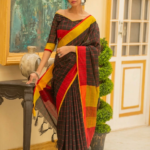 An Indian model showcases a black checkered Bhagalpuri pure linen saree by Bhavya Lakshmi Fabrics with a striking red and yellow border, featuring a matching off-shoulder blouse.