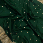 A semi-sheer Bottle Green Organza Banarasi Saree from Bhavya Lakshmi Fabrics, featuring handwoven golden zari butis and a detailed floral border.