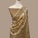 Champagne gold Banarasi Katan silk saree with an all-over gold zari floral jaal pattern and a decorative zari border, draped on a mannequin.
