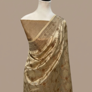 Champagne gold Banarasi Katan silk saree with an all-over gold zari floral jaal pattern and a decorative zari border, draped on a mannequin.