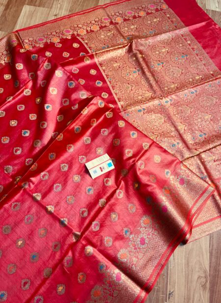 Vibrant crimson red pure Bhagalpuri Munga silk saree from Bhavya Lakshmi Fabrics featuring multi-color floral Meenakari butis and an intricate gold zari border, spread on a wooden floor.