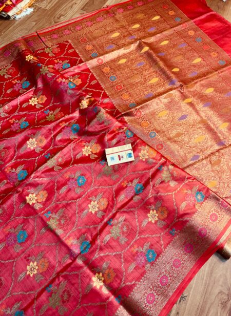 Vibrant crimson red pure Bhagalpuri Munga silk saree from Bhavya Lakshmi Fabrics featuring a multi-color floral Meenakari jaal and an intricate gold zari border, spread on a wooden floor.