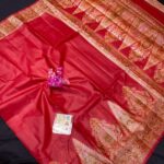 A vibrant crimson red Tussar Banarasi silk saree featuring a thick gold zari border and a heavily woven pallu with traditional floral and paisley motifs.