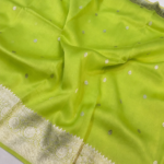 A close-up view of a vibrant Lime Green Organza Banarasi Saree from Bhavya Lakshmi Fabrics featuring detailed handwoven silver zari floral borders and delicate scattered butis.