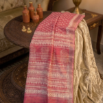 Dusty rose pink linen blend Bhagalpuri saree featuring white geometric Bagru prints and elegant pompom tassels.