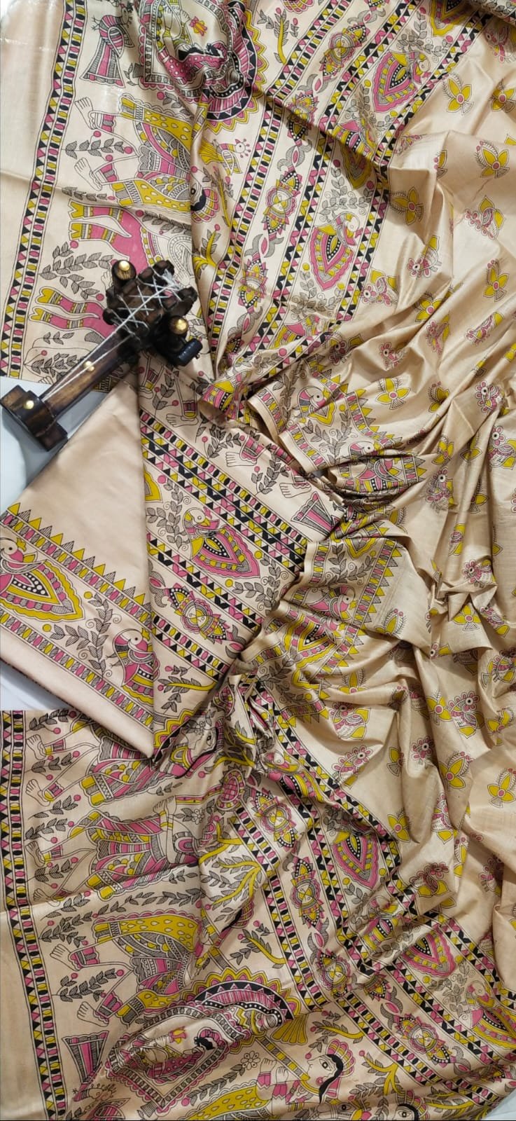 Madhubani Print Unstitched Katan Silk Suit Material by Bhavya Lakshmi Fabrics A premium unstitched beige Katan silk suit material set by Bhavya Lakshmi Fabrics featuring detailed multicolored Madhubani art hand-painted style prints on the top, bottom, and dupatta.