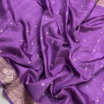A full-length view of a luxurious Mauve Purple Organza Banarasi Saree from Bhavya Lakshmi Fabrics displaying delicate golden zari butis and a grandly detailed floral zari pallu.