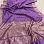 A full-length view of a luxurious Mauve Purple Organza Banarasi Saree from Bhavya Lakshmi Fabrics displaying delicate golden zari butis and a grandly detailed floral zari pallu.