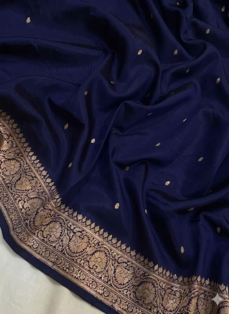 A semi-sheer Navy Blue Organza Banarasi Saree from Bhavya Lakshmi Fabrics, featuring handwoven golden zari butis and a grand floral border.