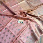 Elegant pastel peach pure Bhagalpuri Muga silk saree from Bhavya Lakshmi Fabrics featuring multi-color floral butis and an intricate gold zari border