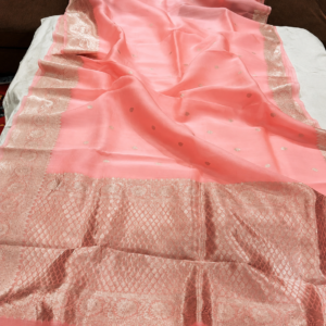 A close-up view of a serene Peach Organza Banarasi Saree from Bhavya Lakshmi Fabrics featuring detailed handwoven metallic zari borders and delicate scattered butis.