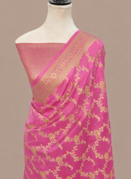 Rani pink Banarasi Katan silk saree with an all-over gold zari floral jaal pattern and a decorative zari border, draped on a mannequin