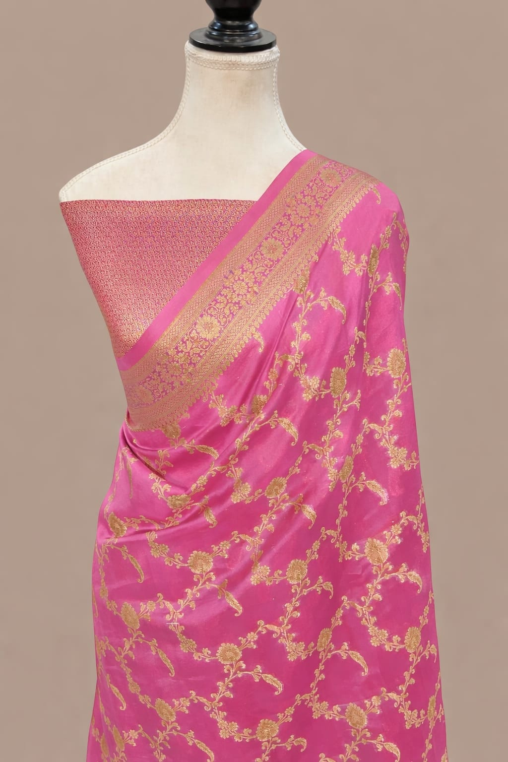 Pink Banarasi SIlk saree by Bhavya Lakshmi Fabrics Rani pink Banarasi Katan silk saree with an all-over gold zari floral jaal pattern and a decorative zari border, draped on a mannequin