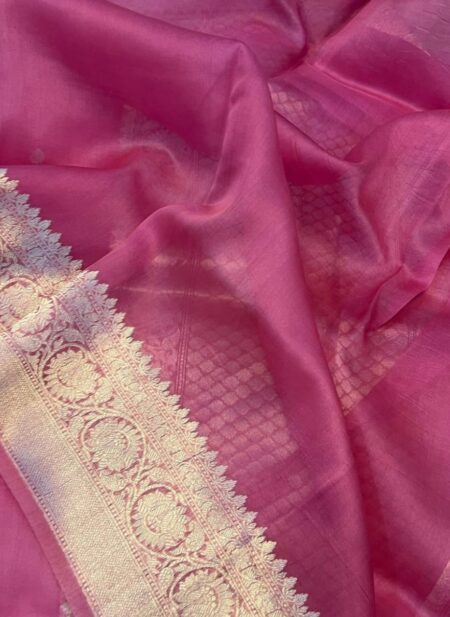 A close-up view of a vibrant Rani Pink Organza Banarasi Saree from Bhavya Lakshmi Fabrics featuring detailed handwoven silver zari floral borders and subtle self-textured check patterns.