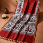 A deep red Kota silk Bhagalpuri saree from Bhavya Lakshmi Fabrics featuring detailed multicolored Madhubani art prints of folklore figures and ritual animals.