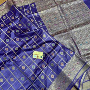 Vibrant royal purple pure Bhagalpuri Munga silk saree from Bhavya Lakshmi Fabrics featuring gold zari checks with multi-color floral Meenakari butis and an intricate gold zari border, spread on a wooden floor.