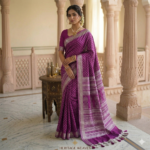 Royal purple linen blend Bhagalpuri saree featuring white geometric Bagru prints and elegant pompom tassels.