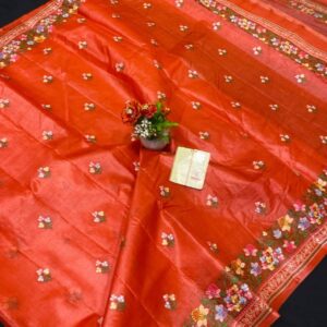A vibrant rust orange pure Bhagalpuri Munga silk handloom saree from Bhavya Lakshmi Fabrics featuring detailed multicolored floral embroidery scattered butis and an ornate floral border.