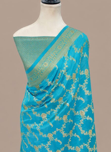 Turquoise blue Banarasi Katan silk saree with an all-over gold zari floral jaal pattern and a decorative zari border, draped on a mannequin