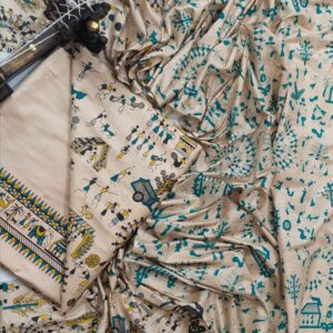 An unstitched beige Katan silk suit material set by Bhavya Lakshmi Fabrics featuring detailed teal blue and mustard yellow Warli tribal dance prints, geometric borders, and a matching dupatta