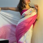 An Indian model showcases a white pure linen saree by Bhavya Lakshmi Fabrics featuring colorful floral embroidery across the shoulder and a vibrant magenta pink border.