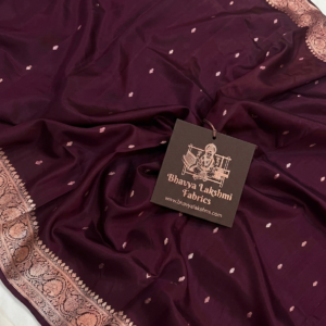 A semi-sheer Wine Organza Banarasi Saree from Bhavya Lakshmi Fabrics, showcasing handwoven golden zari butis and a detailed floral border.