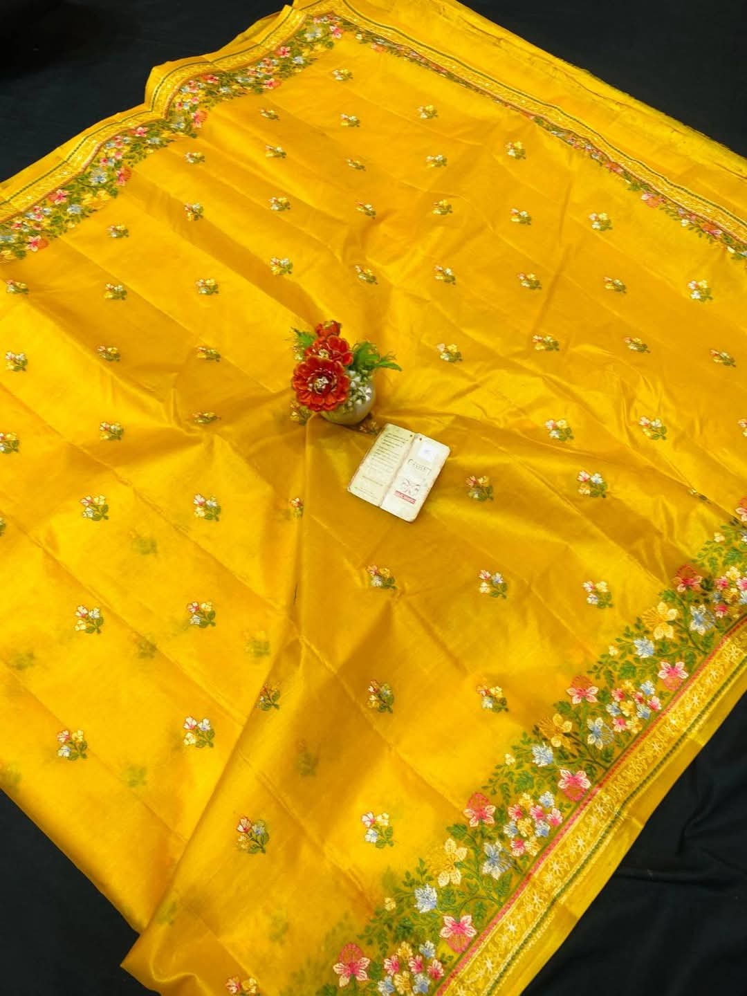 Yellow Pure Bhagalpuri Munga Silk Saree by Bhavya Lakshmi Fabrics A vibrant yellow pure Bhagalpuri Munga silk handloom saree from Bhavya Lakshmi Fabrics featuring detailed multicolored floral embroidery scattered butis and an ornate floral border.