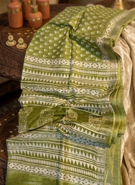Sophisticated olive green linen blend Bhagalpuri saree featuring white geometric Bagru prints and elegant pompom tassels.