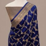 Royal blue Banarasi Katan silk saree featuring an all-over gold zari floral jaal pattern and a decorative zari border, draped on a mannequin.