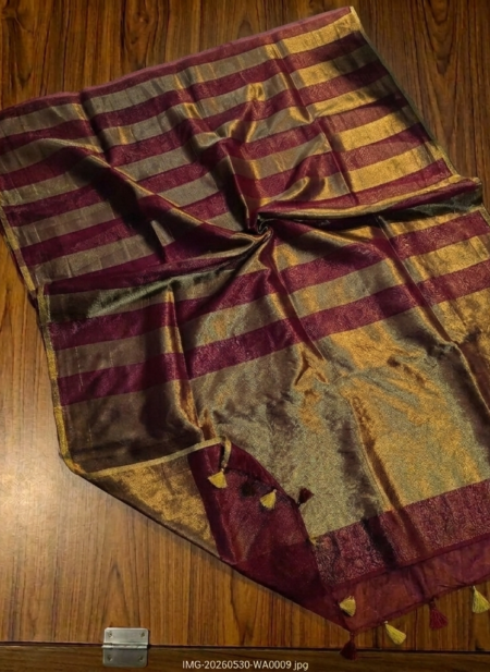 Rich maroon and metallic gold zari striped tissue silk saree featuring intricate borders and matching tassel details.