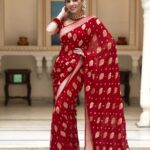 Vibrant bridal red semi organza saree featuring woven golden zari floral buttas and a matching patterned blouse.