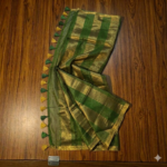 Sophisticated olive green and metallic gold zari striped tissue silk saree featuring intricate borders and matching tassel details.