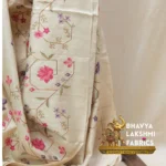 Bhavyaloom natural cream 100 percent pure tussar muga silk saree with pink and purple floral hand embroidery draped on wooden stand