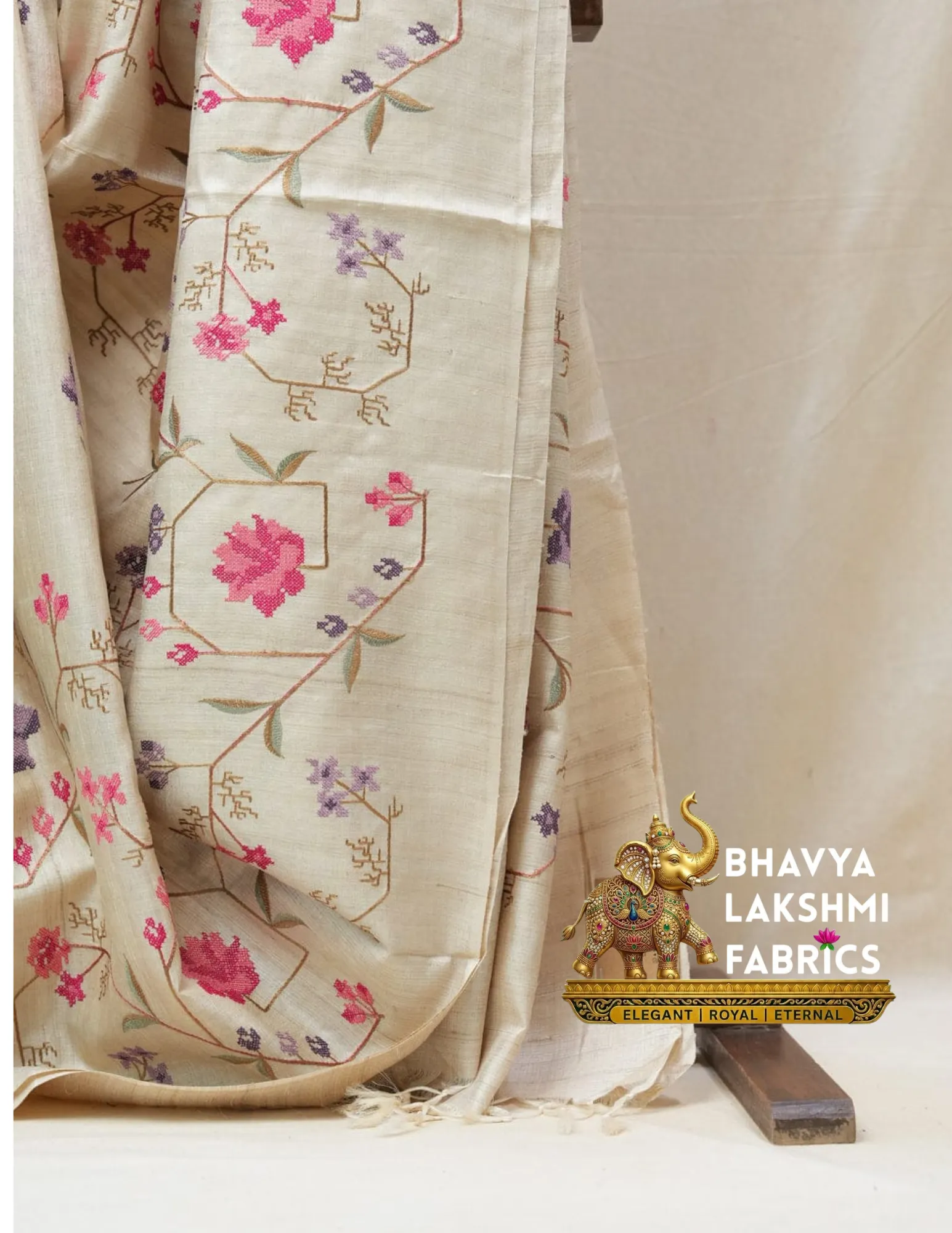 100% Pure Tussar Muga Silk Saree – Natural Cream Traditional Floral Embroidery Luxury Saree by Bhavyaloom_result Bhavyaloom natural cream 100 percent pure tussar muga silk saree with pink and purple floral hand embroidery draped on wooden stand