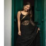 Bhavyaloom jet black bhagalpuri kota doria embroidery saree with thin gold zari border on model in front of green door
