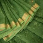 Bhavyaloom moss green bhagalpuri kota doria embroidery saree with gold border draped on model sitting on chair